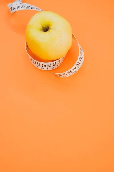 Ett Äpple Med Måttband Isolerad Orange Bakgrund — Stockfoto