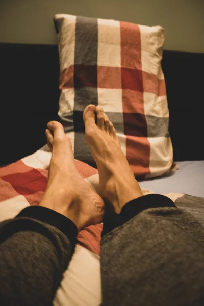 Een Verticaal Schot Van Iemands Voeten Liggend Een Bed Met — Stockfoto