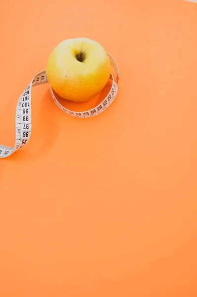 Ein Apfel Mit Maßband Isoliert Auf Orangefarbenem Hintergrund — Stockfoto