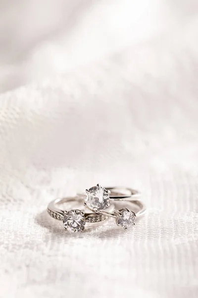 Függőleges Elszigetelt Közelkép Gyémánt Gyűrűk Egy Fehér Csipke Háttér — Stock Fotó