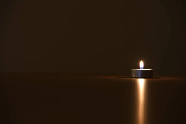 Nahaufnahme Einer Brennenden Kleinen Kerze Mit Lichtreflexion Auf Einer Tischfläche — Stockfoto