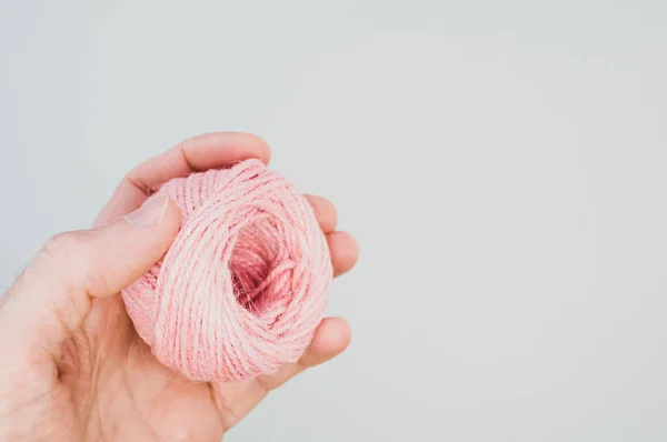 用一只手拿着粉色纱球织毛衣的特写镜头 — 图库照片