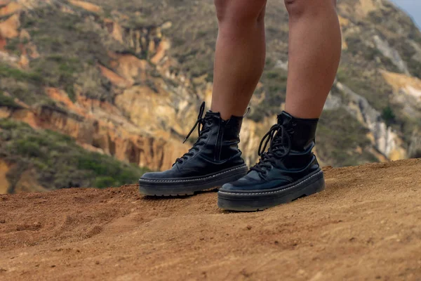 Female feet wearing black boots standing on the rock in the desert in Columbia