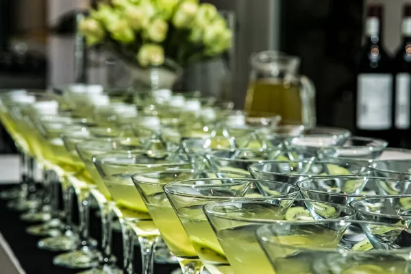 黄色のさわやかな飲み物で満たされた透明なガラスのテーブル — ストック写真