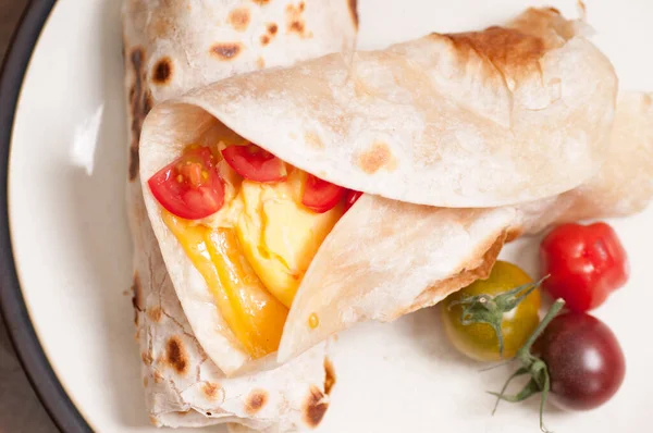 breakfast burrito with cheese, eggs and heirloom cherry tomato