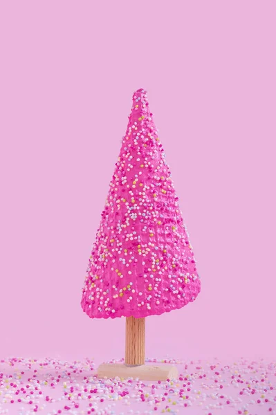 ピンクの背景にピンクのプラスチック製のクリスマスツリーの垂直ショット — ストック写真