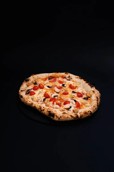 黒の表面においしいピザの垂直ショット — ストック写真