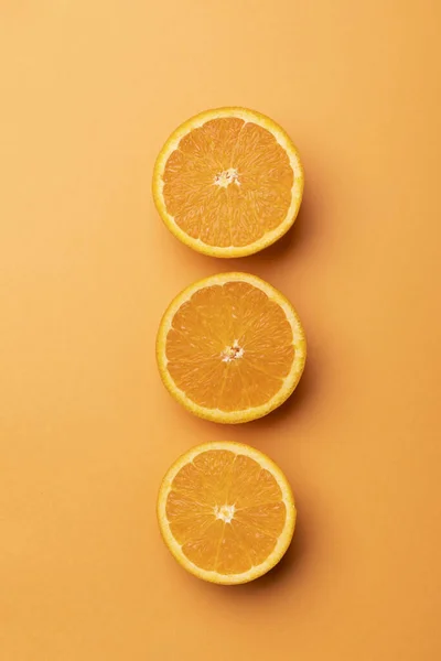オレンジの背景に半分にスライスされたオレンジ色の果実の垂直方向のクローズアップ — ストック写真