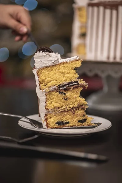 プレート上に食欲をそそるケーキの一部を入れて手の垂直選択的フォーカスショット — ストック写真
