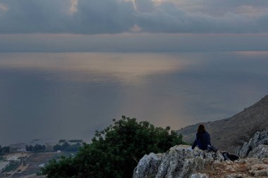 A young woman enjoying the sunrise over the Sea of Galilee and Golan Heights clipart
