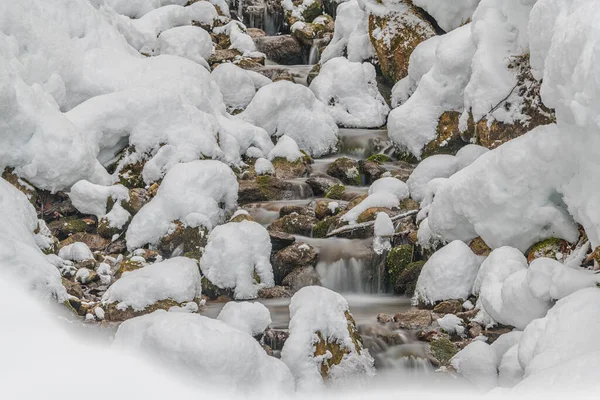 一条山溪流过白雪覆盖的岩石的美丽景色 — 图库照片