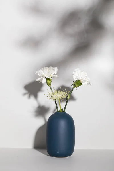 Disparo Vertical Flores Enmalle Blancas Jarrón Azul Contra Una Pared — Foto de Stock