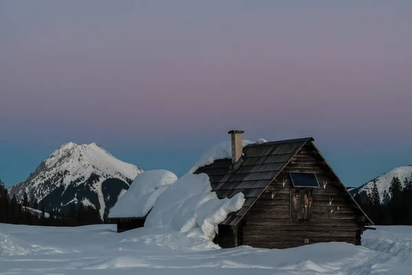 Piękny Widok Drewniany Dom Pokryty Śniegiem Podczas Zachodu Słońca — Zdjęcie stockowe