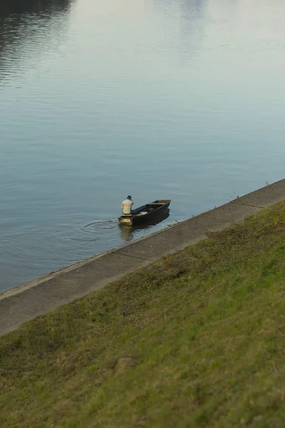 ボートや釣りに座っている男と川や草のコントラスト — ストック写真