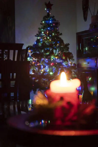 一支燃烧的蜡烛和一棵美丽的圣诞树 还有五彩缤纷的彩灯 — 图库照片