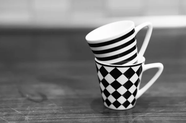 A grayscale shot of mugs with striped and chess tile patterns