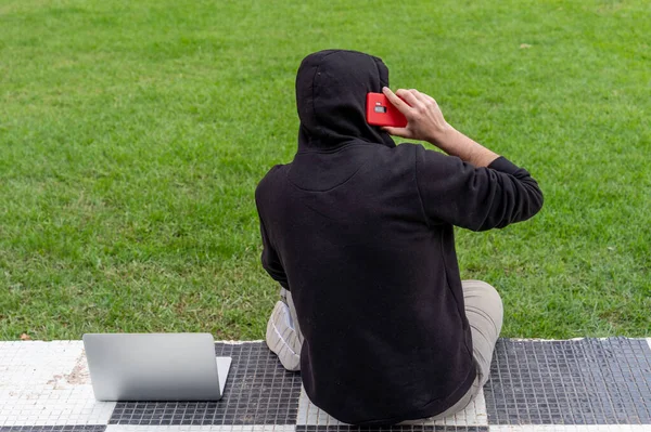 Een Jongeman Met Een Capuchon Een Park Met Zijn Laptop — Stockfoto