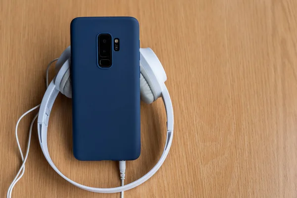 Eine Hochwinkelaufnahme Eines Blauen Handys Mit Kopfhörern Auf Einer Holzoberfläche — Stockfoto