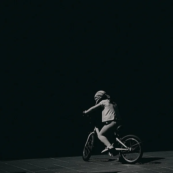 Graustufenaufnahme Eines Kindes Auf Einem Fahrrad Vor Dunklem Hintergrund — Stockfoto