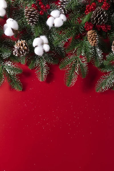 Вертикальний Знімок Штучних Ялинових Гілок Різдвяними Прикрасами Ізольовані Червоному Тлі — стокове фото