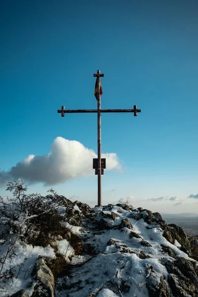 旗を掲げて岩の上に立つキリスト教徒の金属製の十字架の垂直ショット — ストック写真
