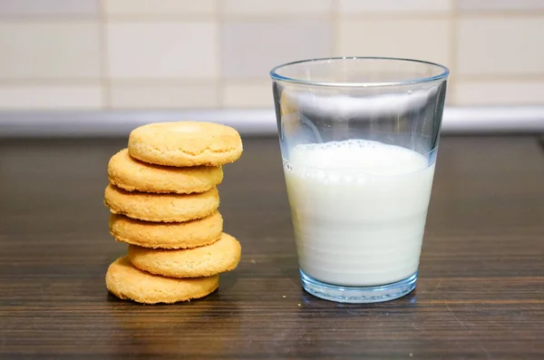一杯牛奶和饼干在木制表面上的近照 — 图库照片