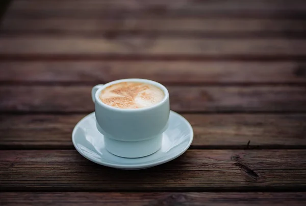Tiro Foco Seletivo Cappuccino Uma Xícara Branca Uma Mesa Madeira — Fotografia de Stock