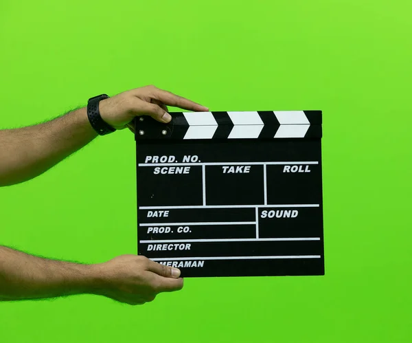 Men\'s hand holding camera slate for the filming isolated on green background. clapperboard in chroma