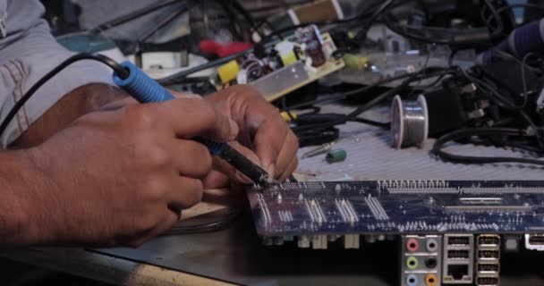 技術者は コンピュータ回路基板の概念技術の電子を修復するためにハンダ付け鉄を使用していますコンピュータ回路ハードウェア — ストック動画