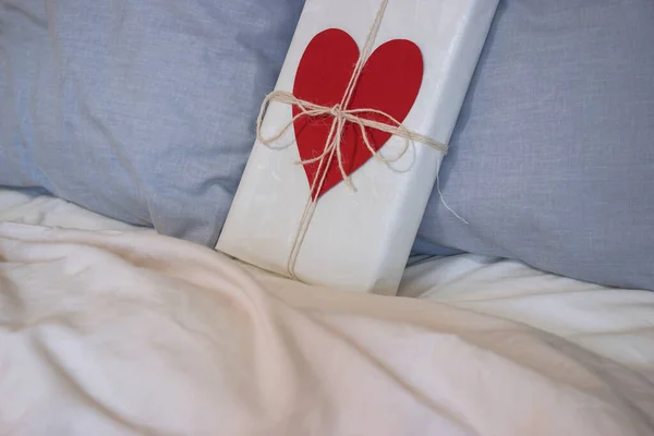 리본과 심장이 선물을 발렌타인 데이를 사랑하는 부부의 침대에 놓는다 — 스톡 사진