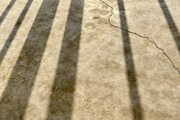 风化裂缝混凝土地板上的栏杆阴影 — 图库照片