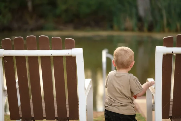 湖によって椅子の近くにかわいいブロンドの子供の浅いフォーカスショット — ストック写真