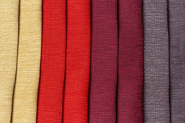 Saturated colors of a set of comparison interior decoration sample swaps of textured curtain fabric with various shades and colorful backdrop