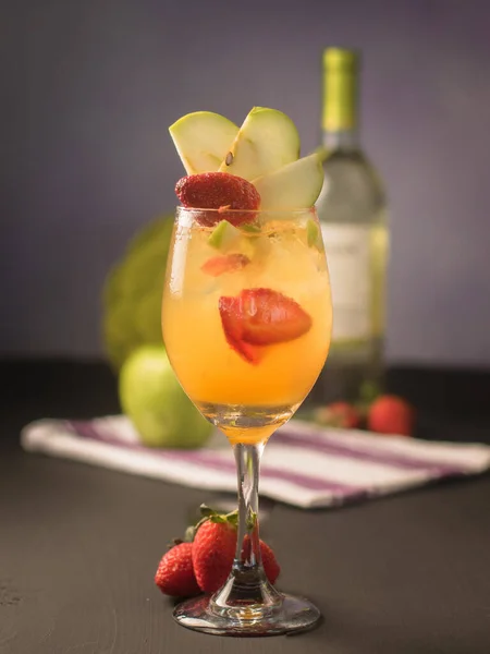 A closeup of lemon sangria cocktail with strawberry and apple