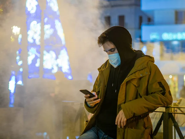 Een Jonge Man Een Gezichtsmasker Controleert Zijn Telefoon Een Brug — Stockfoto