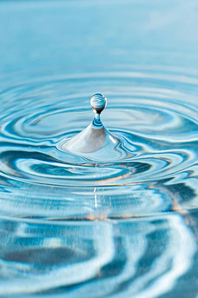 Een Verticaal Schot Van Een Waterdruppel Het Blauwe Water — Stockfoto