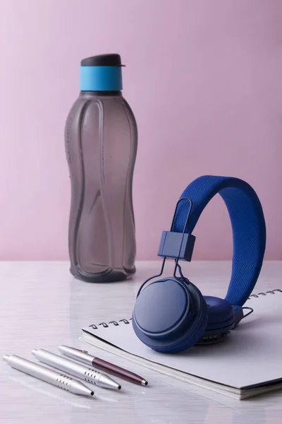 Una Toma Vertical Una Botella Con Auriculares Cuaderno Bolígrafos Sobre — Foto de Stock