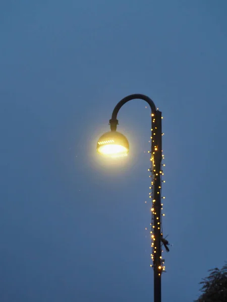 Tiro Vertical Uma Lâmpada Rua Com Luzes Natal Embrulhadas Poste — Fotografia de Stock
