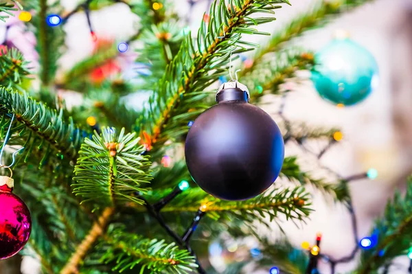 Ledライトで飾られたクリスマスツリー上の黒いクリスマスボールのクローズアップショット — ストック写真