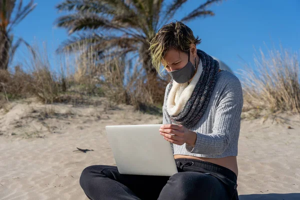 마스크를 여자가 해변에서 노트북으로 일하고 — 스톡 사진