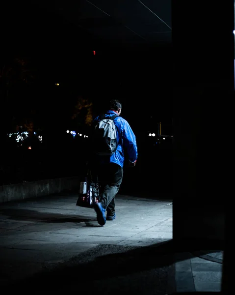 夜の仕事から家に帰るリュックとハンドバッグを持った男の垂直ショット — ストック写真