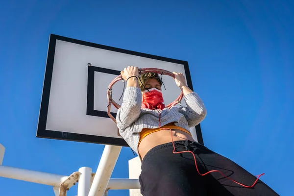 Een Vrouw Met Een Gezichtsmasker Grijpend Hangend Aan Een Basketbalring — Stockfoto