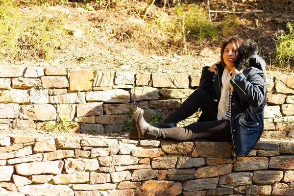 Una Giovane Donna Ispanica Cappotto Seduta Muro Pietra Nel Parco — Foto Stock