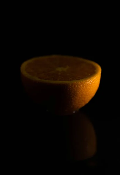 Pionowe Ujęcie Naciętej Mokrej Połowy Pomarańczy Jej Odbicie Odizolowanym Czarnym — Zdjęcie stockowe