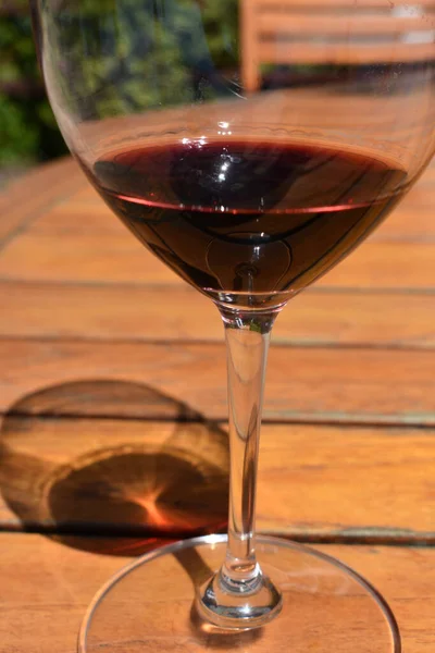 红葡萄酒杯的一个垂直的镜头 在木制桌子上有阴影 — 图库照片