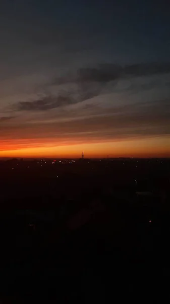 Eine Vertikale Aufnahme Eines Orangen Sonnenuntergangs Über Einer Dunklen Stadt — Stockfoto