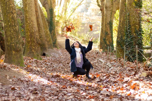 Μια Χαρούμενη Ισπανόφωνη Γυναίκα Γονατισμένη Ρίχνοντας Φύλλα Φθινοπώρου Στον Αέρα — Φωτογραφία Αρχείου