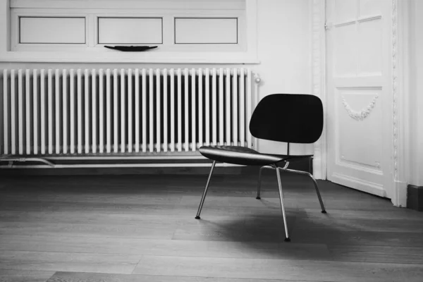 Graustufenaufnahme Eines Einfachen Stuhls Einem Raum Gegen Eine Wandheizung — Stockfoto