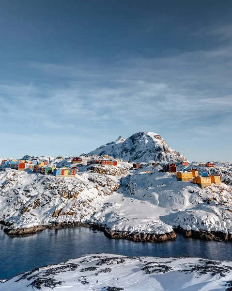 格陵兰岛一条冰冻的河流边雪山上的一座五彩斑斓的房屋的垂直拍摄 — 图库照片