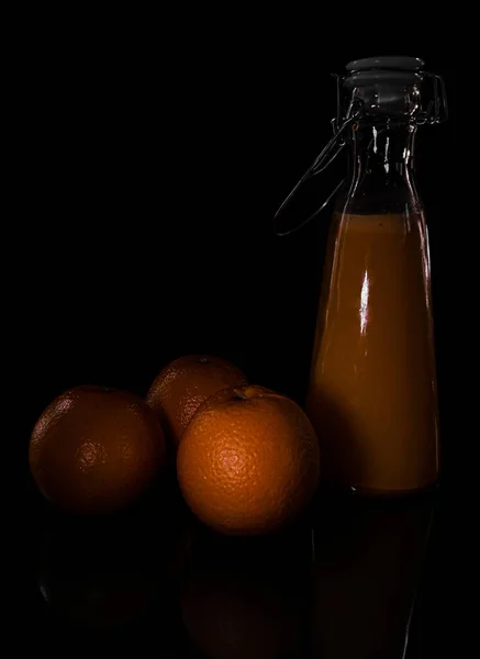 Вертикальный Снимок Апельсинов Бутылка Сока Черном Фоне Тенью — стоковое фото